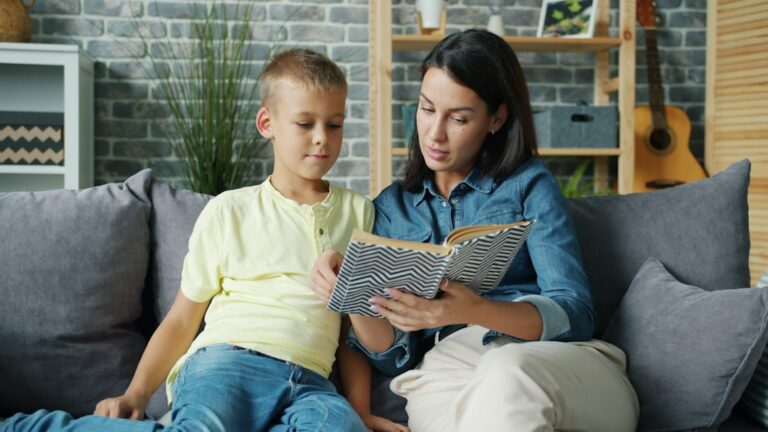 Parent and child practice letter sounds together with a book and letter cards at a kitchen table.