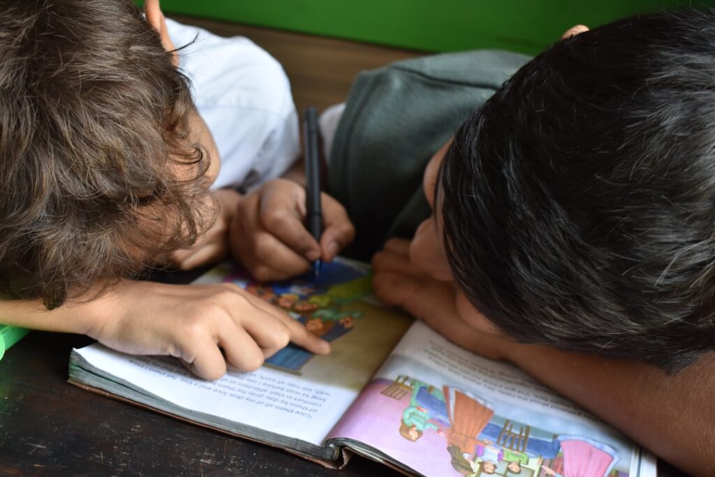 Student reading with an adult while a notebook and letter cards rest on the table.