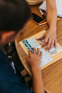 A parent and teacher review a child’s reading samples and classroom notes at a school meeting.