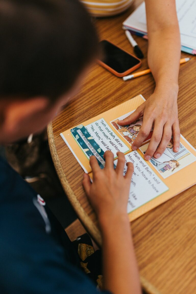A parent and teacher review a child’s reading samples and classroom notes at a school meeting.